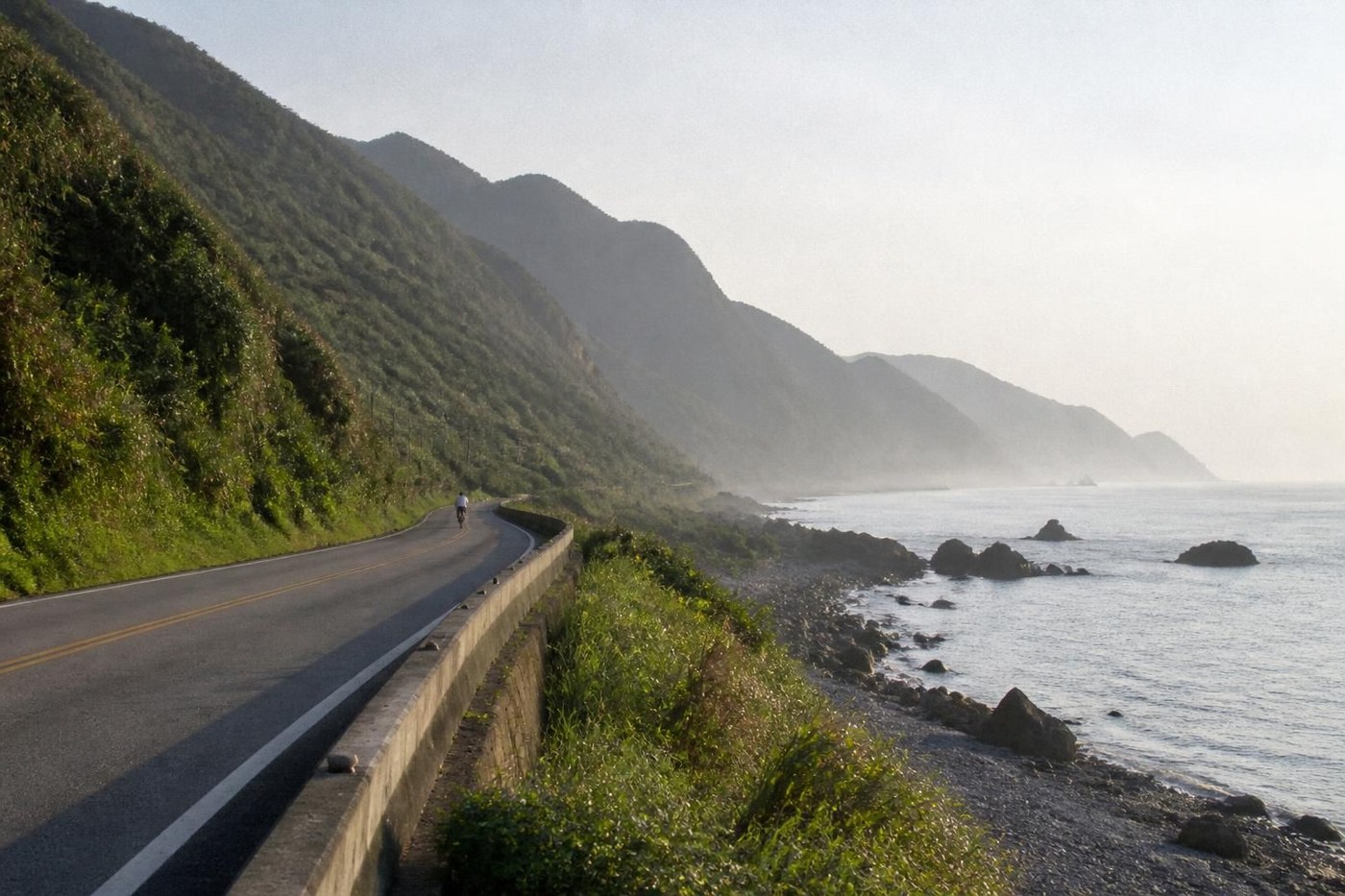 Carretera costera de montaña en Taiwán con un ciclista a lo lejos